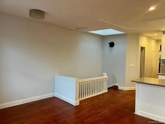 Unfurnished room featuring dark wood-style flooring, a skylight, and recessed lighting Unfurnished room featuring dark wood-style flooring, a skylight, and recessed lighting
