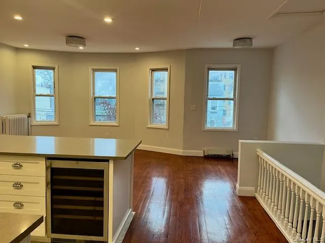 Kitchen with beverage cooler, radiator heating unit, recessed lighting, healthy amount of natural light, and dark wood-type flooring Kitchen with beverage cooler, radiator heating unit, recessed lighting, healthy amount of natural light, and dark wood-type flooring