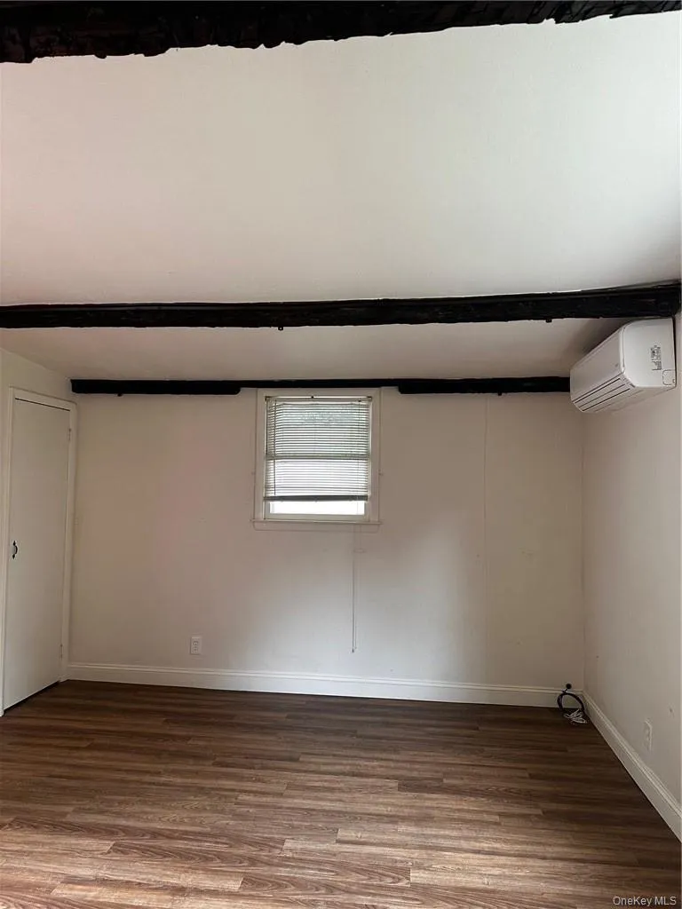 Basement featuring a wall unit AC and hardwood / wood-style flooring Basement featuring a wall unit AC and hardwood / wood-style flooring