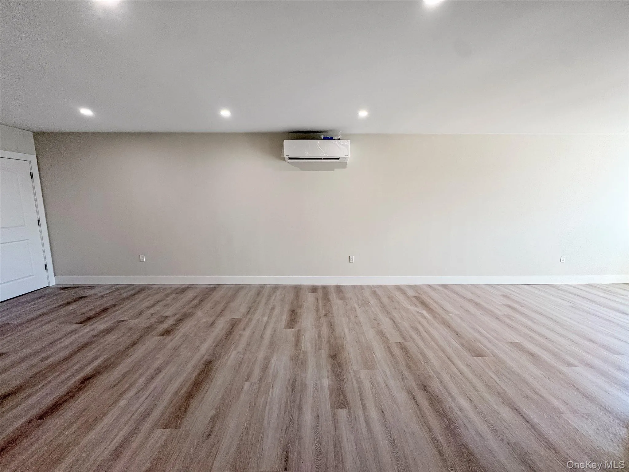 Basement featuring light wood-style floors, recessed lighting, and a wall unit AC Basement featuring light wood-style floors, recessed lighting, and a wall unit AC