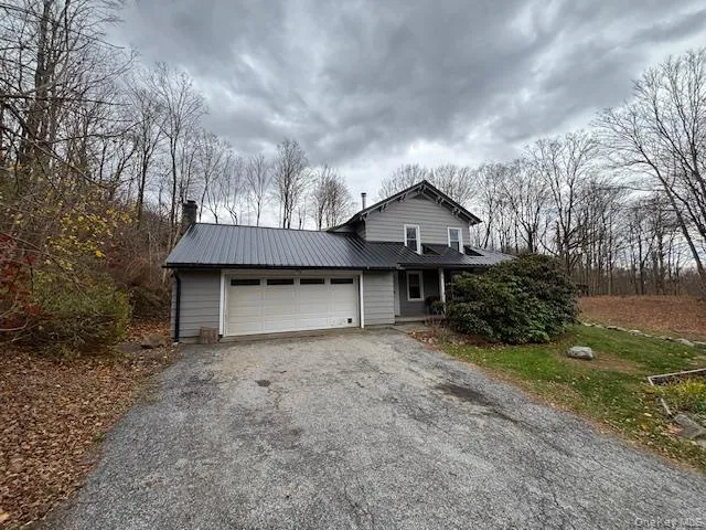 View of front of property featuring asphalt driveway, an attached garage, a metal roof, and a chimney View of front of property featuring asphalt driveway, an attached garage, a metal roof, and a chimney