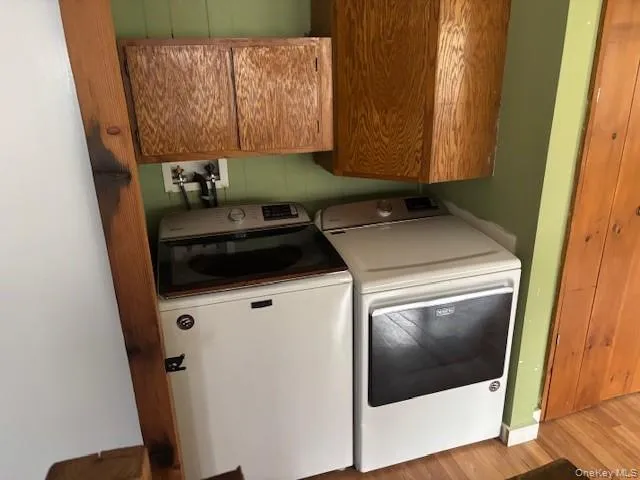 Laundry room featuring cabinet space, light wood-style flooring, and washing machine and clothes dryer Laundry room featuring cabinet space, light wood-style flooring, and washing machine and clothes dryer