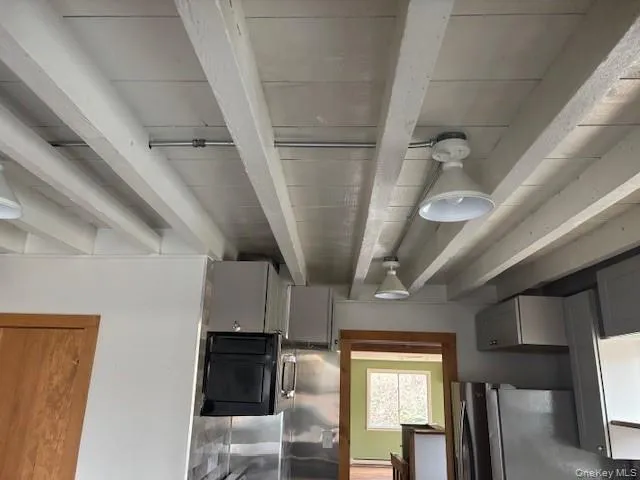 Kitchen view of gray cabinets, beamed ceiling, and freestanding refrigerator Kitchen view of gray cabinets, beamed ceiling, and freestanding refrigerator
