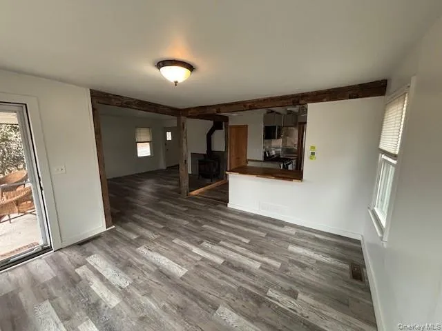 Unfurnished living room with a wood stove and wood finished floors Unfurnished living room with a wood stove and wood finished floors