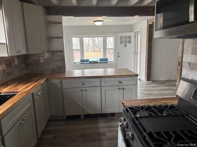 Kitchen featuring butcher block countertops, open shelves, stainless steel appliances, dark wood-style floors, and beamed ceiling Kitchen featuring butcher block countertops, open shelves, stainless steel appliances, dark wood-style floors, and beamed ceiling