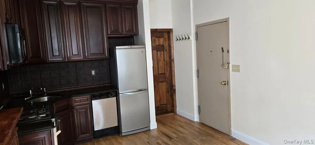 Kitchen featuring dark brown cabinets, decorative backsplash, stainless steel appliances, and dark wood-type flooring Kitchen featuring dark brown cabinets, decorative backsplash, stainless steel appliances, and dark wood-type flooring