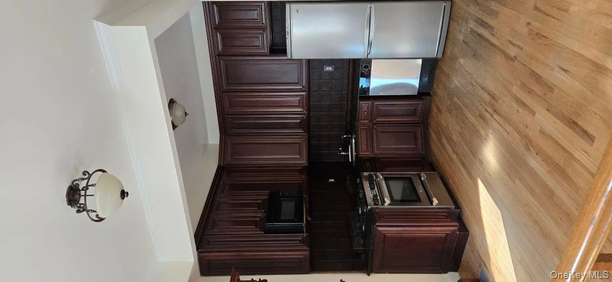 Kitchen featuring stainless steel appliances, dark brown cabinetry, light wood finished floors, crown molding, and backsplash Kitchen featuring stainless steel appliances, dark brown cabinetry, light wood finished floors, crown molding, and backsplash