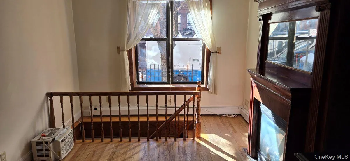 Stairs featuring wood finished floors, a baseboard radiator, and a wall mounted AC Stairs featuring wood finished floors, a baseboard radiator, and a wall mounted AC
