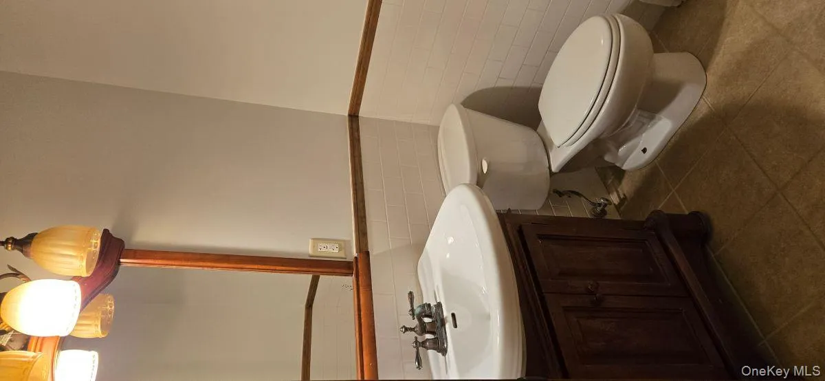 Bathroom with wainscoting, vanity, tile walls, and dark tile patterned floors Bathroom with wainscoting, vanity, tile walls, and dark tile patterned floors