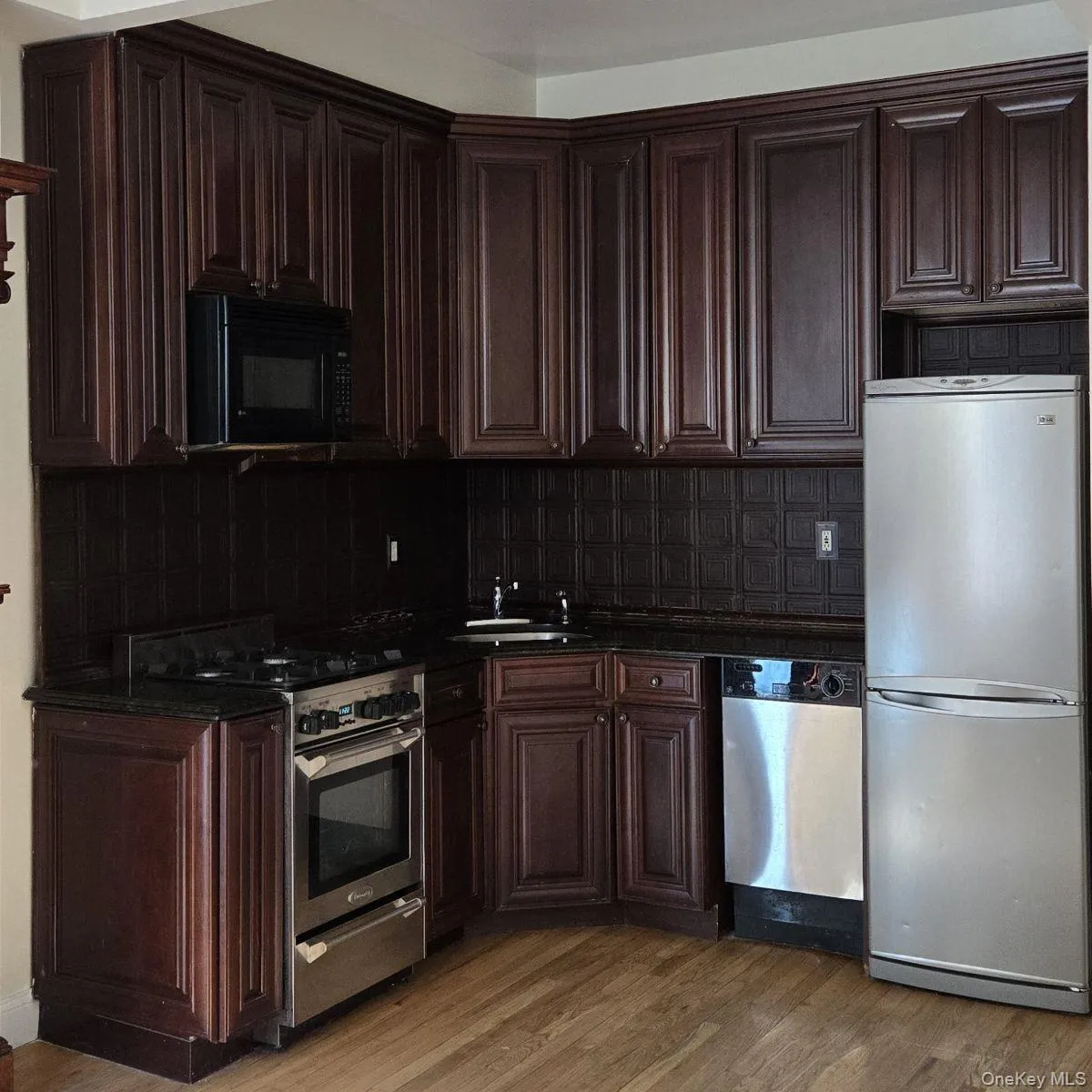 Kitchen with dark brown cabinetry, appliances with stainless steel finishes, light wood-style flooring, and tasteful backsplash Kitchen with dark brown cabinetry, appliances with stainless steel finishes, light wood-style flooring, and tasteful backsplash