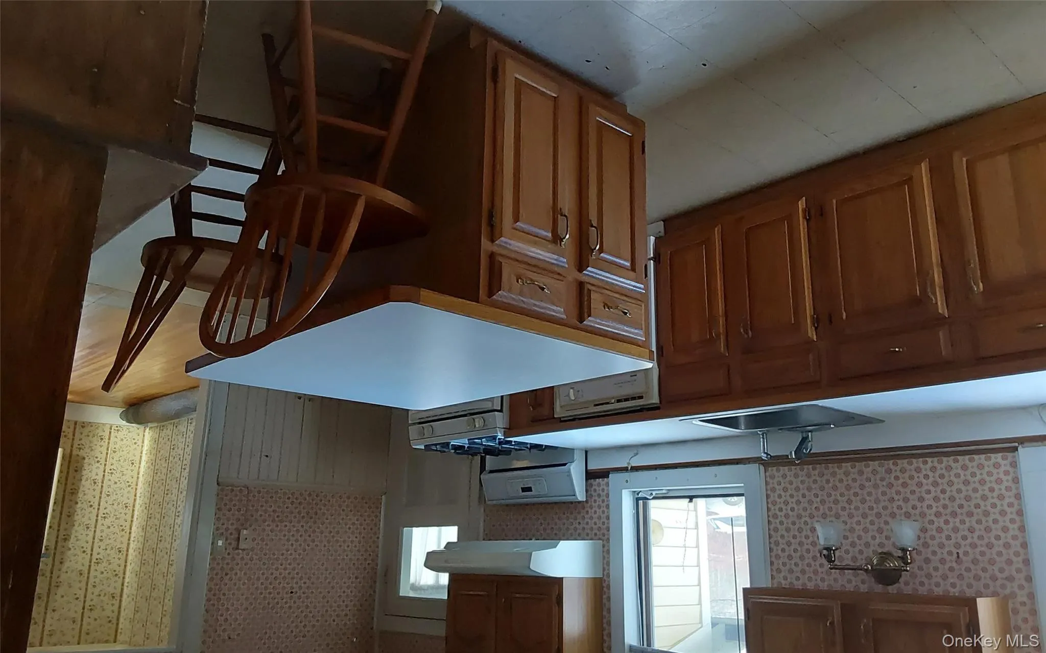 Kitchen with a breakfast bar, stove, a kitchen island, light countertops, and brown cabinetry Kitchen with a breakfast bar, stove, a kitchen island, light countertops, and brown cabinetry
