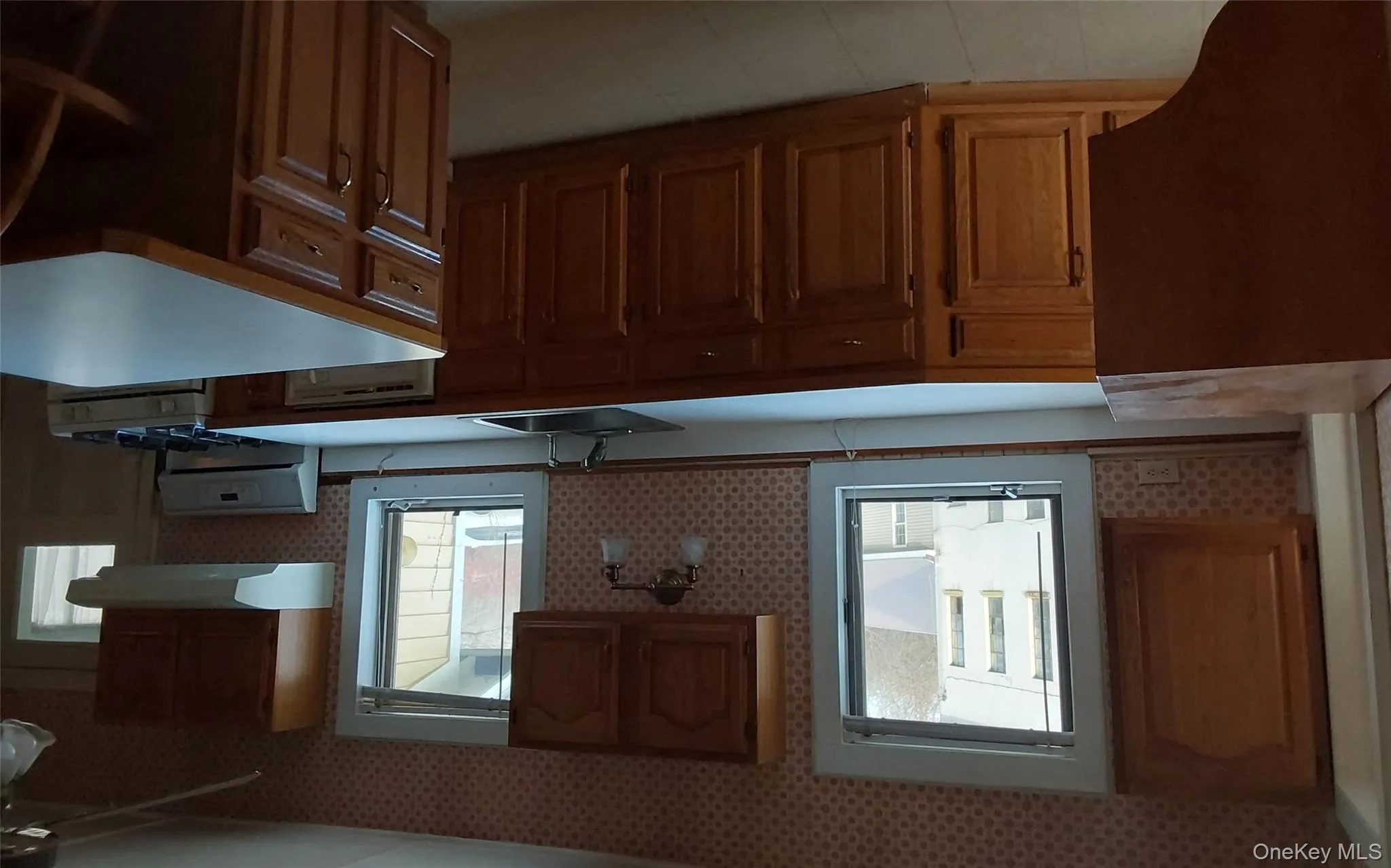 Kitchen featuring light countertops, range, brown cabinets, light floors, and range hood Kitchen featuring light countertops, range, brown cabinets, light floors, and range hood