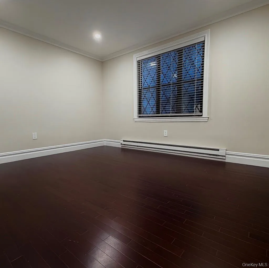 Unfurnished room with ornamental molding, dark wood-style flooring, baseboard heating, and recessed lighting Unfurnished room with ornamental molding, dark wood-style flooring, baseboard heating, and recessed lighting