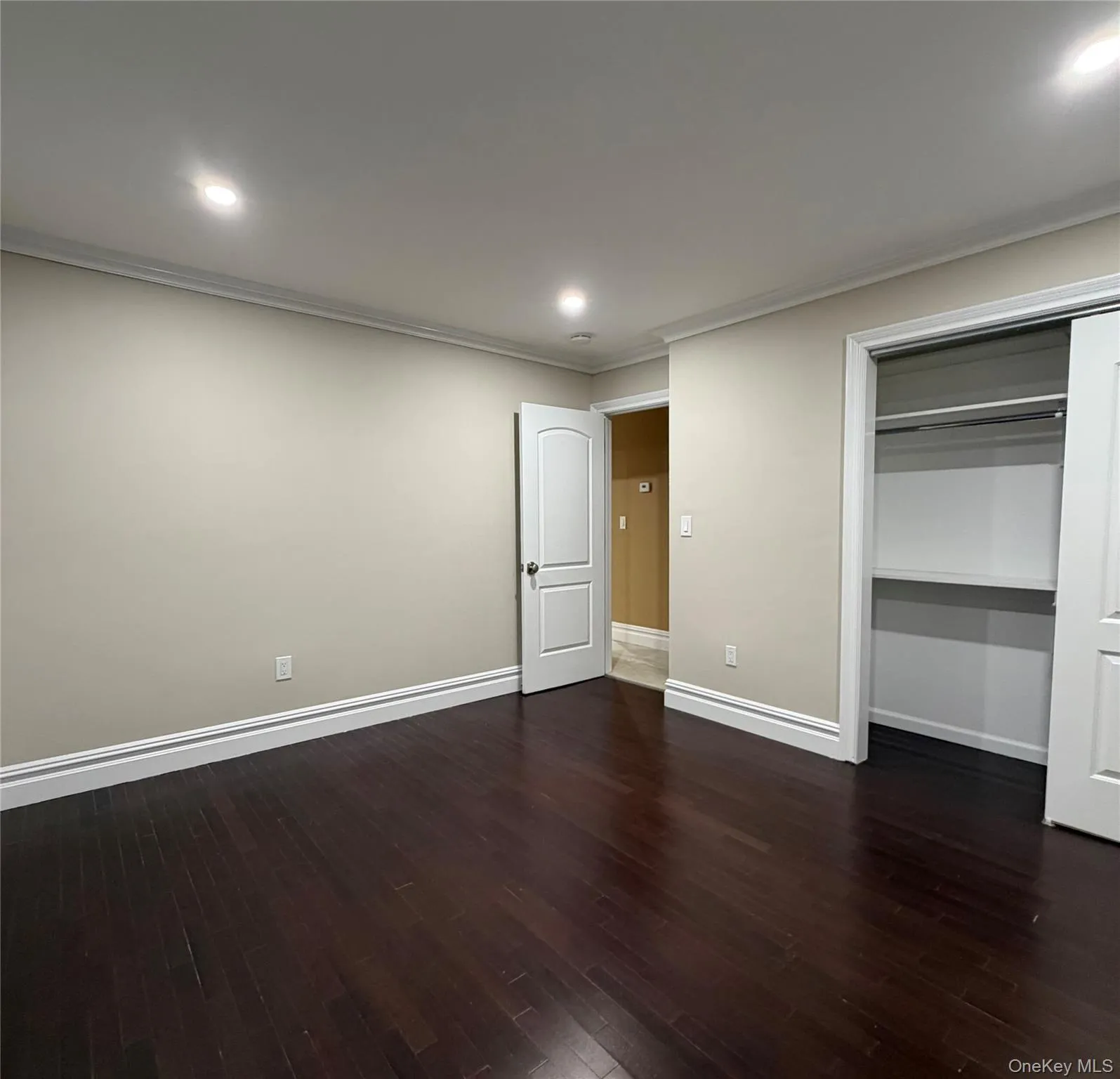 Unfurnished bedroom with recessed lighting, dark wood-style floors, crown molding, and a closet Unfurnished bedroom with recessed lighting, dark wood-style floors, crown molding, and a closet