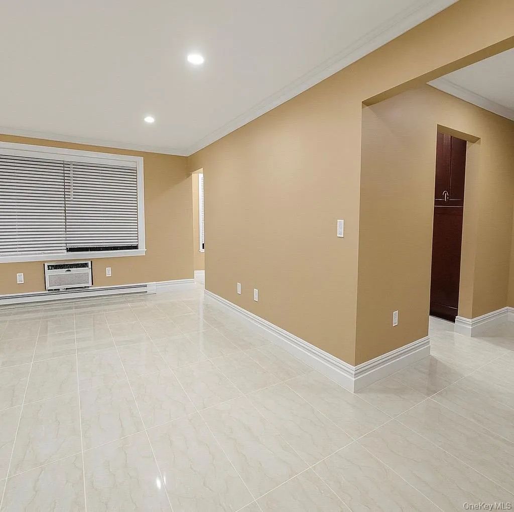 Spare room with ornamental molding, recessed lighting, a baseboard radiator, and a wall mounted air conditioner Spare room with ornamental molding, recessed lighting, a baseboard radiator, and a wall mounted air conditioner