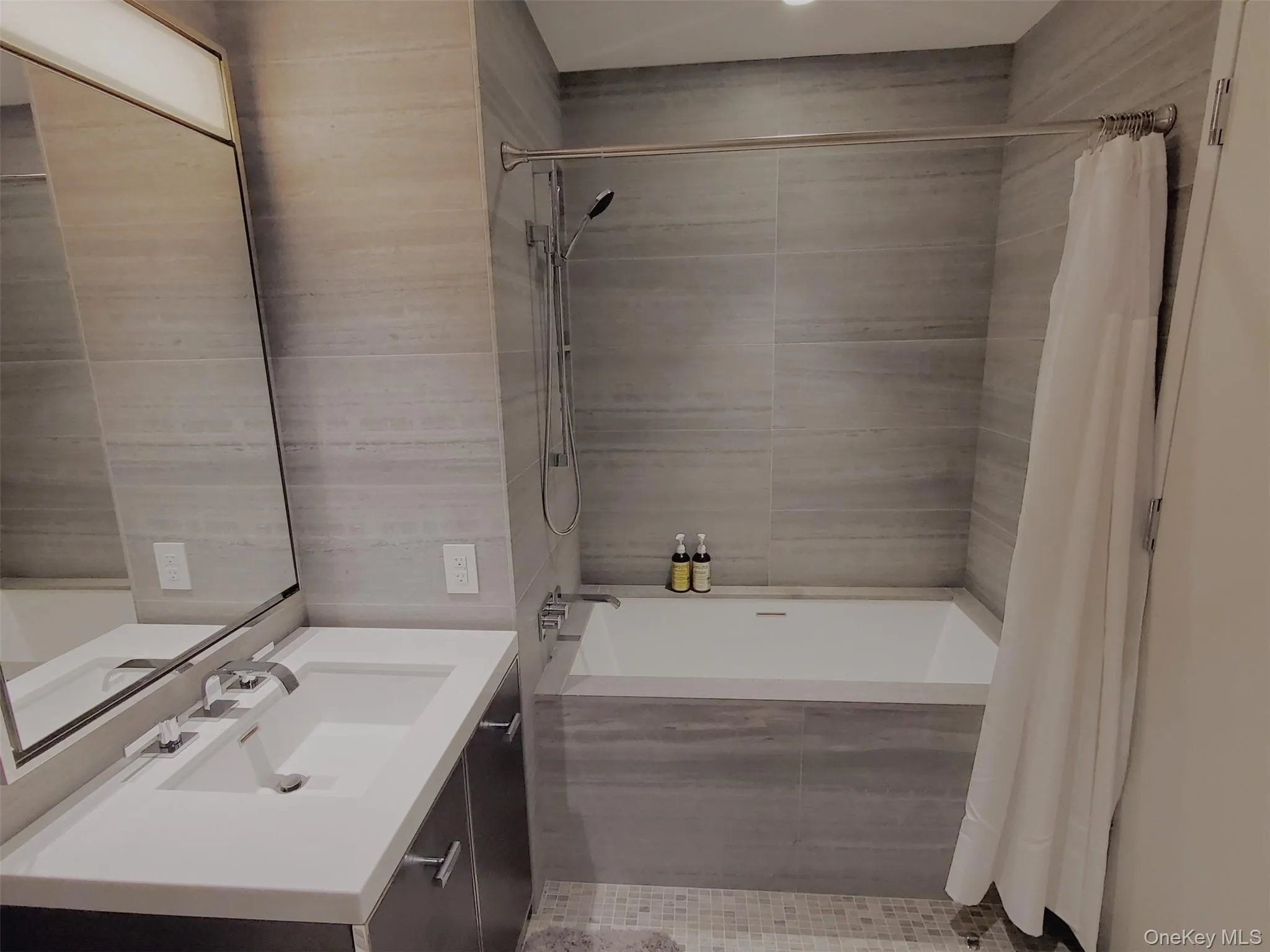 Full bathroom with vanity, tiled shower / bath combo, and tile walls Full bathroom with vanity, tiled shower / bath combo, and tile walls