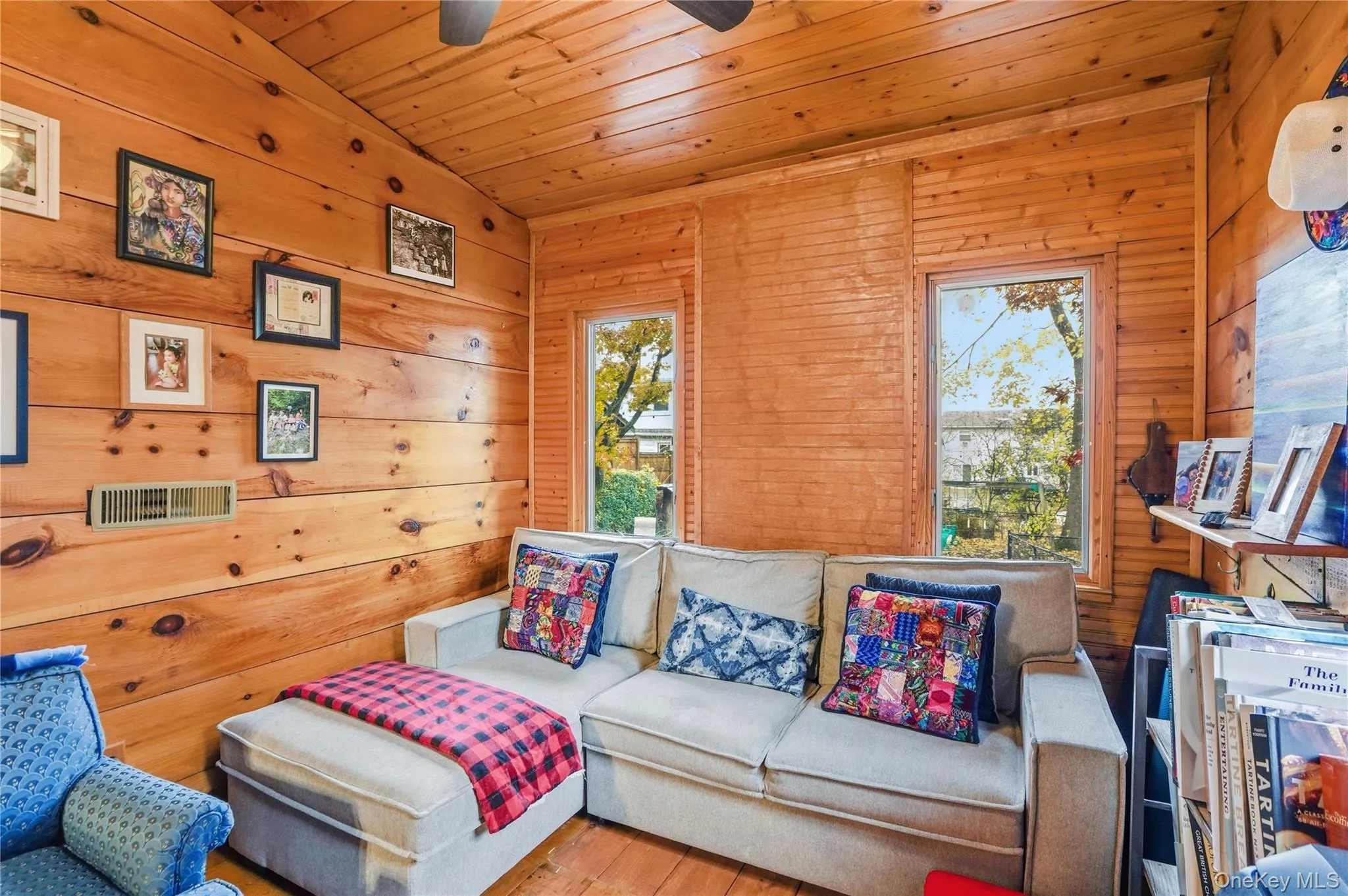 Living room featuring wood ceiling, lofted ceiling, hardwood / wood-style flooring, wooden walls, and a ceiling fan Living room featuring wood ceiling, lofted ceiling, hardwood / wood-style flooring, wooden walls, and a ceiling fan
