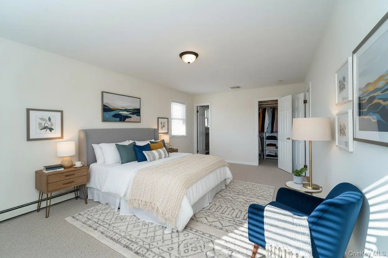 Carpeted bedroom with a walk in closet and baseboard heating Carpeted bedroom with a walk in closet and baseboard heating