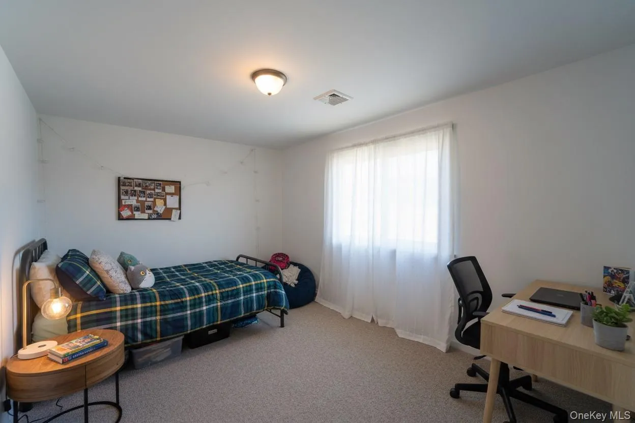 Bedroom featuring light colored carpet and a desk Bedroom featuring light colored carpet and a desk