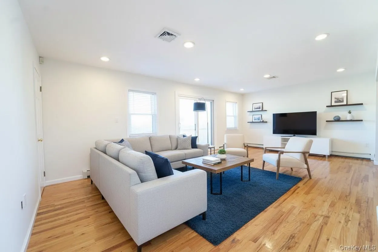 Living area featuring light wood finished floors, recessed lighting, and baseboard heating Living area featuring light wood finished floors, recessed lighting, and baseboard heating