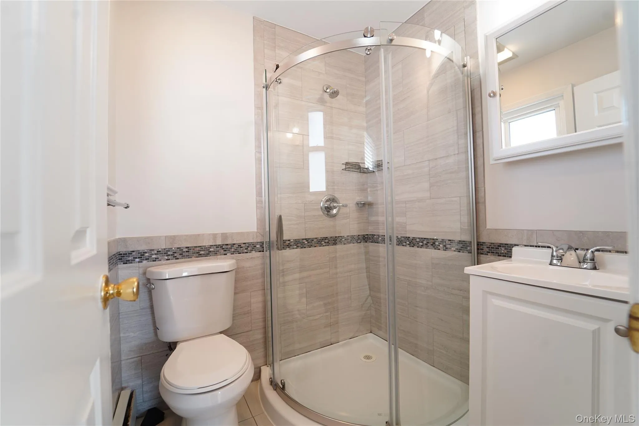Full bathroom with tile walls, vanity, a wainscoted wall, a shower stall, and a baseboard heating unit Full bathroom with tile walls, vanity, a wainscoted wall, a shower stall, and a baseboard heating unit