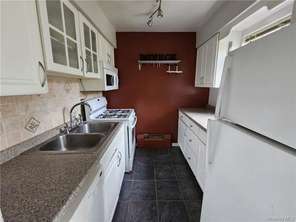Kitchen featuring white appliances, sink, tasteful backsplash, and white cabinets Kitchen featuring white appliances, sink, tasteful backsplash, and white cabinets