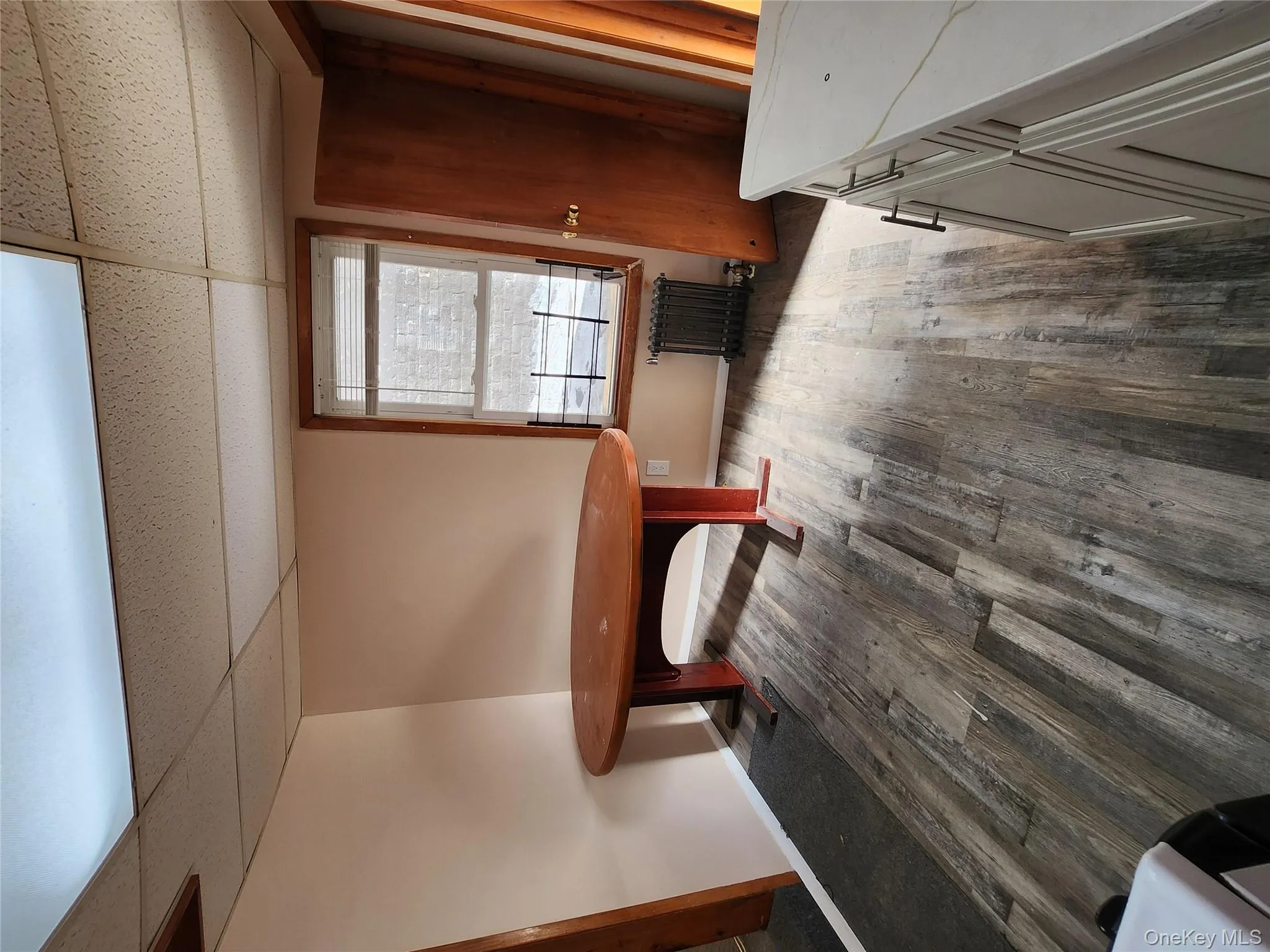 Unfurnished dining area with dark wood-style floors, a paneled ceiling, and radiator heating unit Unfurnished dining area with dark wood-style floors, a paneled ceiling, and radiator heating unit