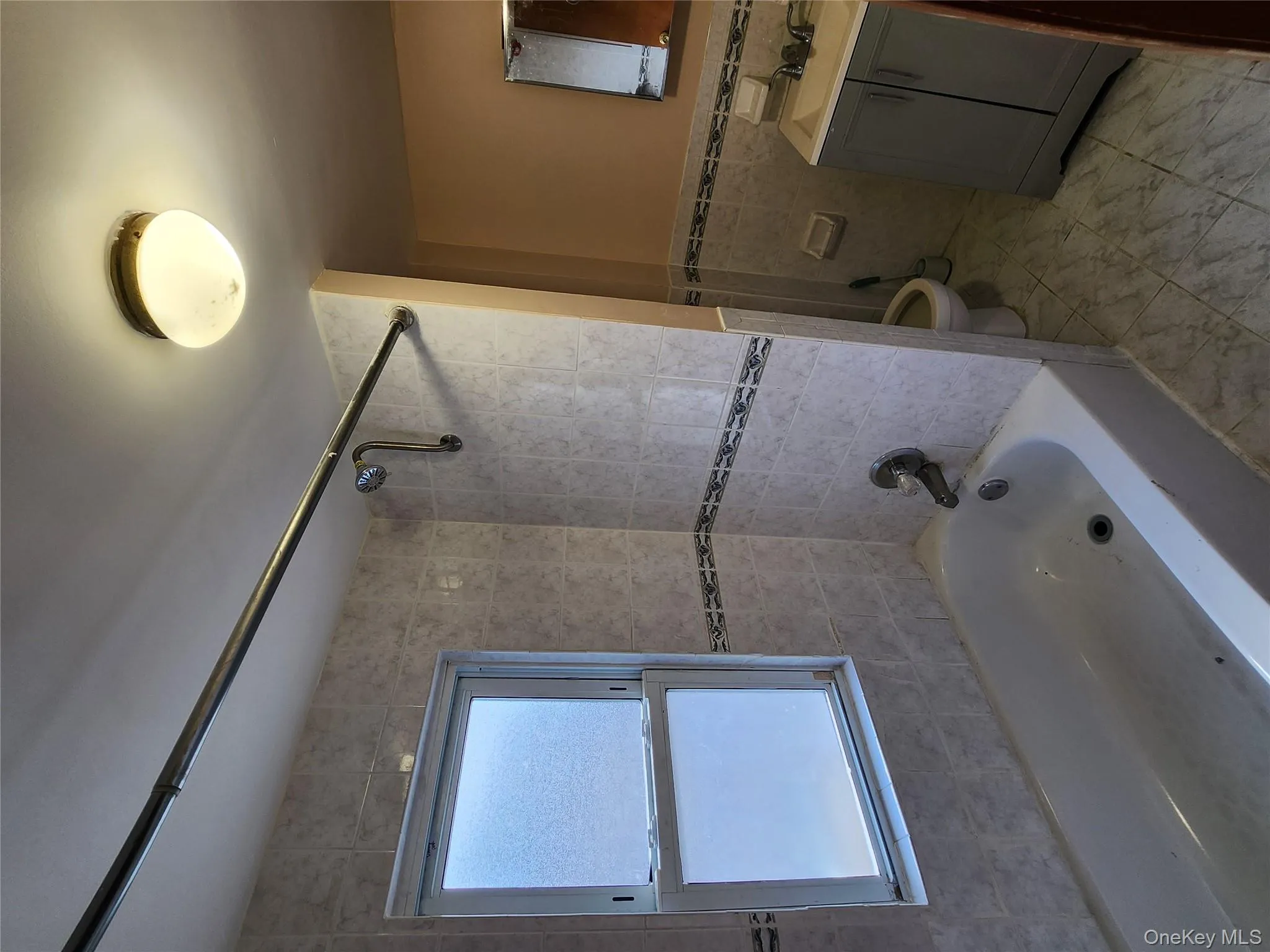 Bathroom featuring vanity, bathtub / shower combination, tile walls, wainscoting, and light marble finish flooring Bathroom featuring vanity, bathtub / shower combination, tile walls, wainscoting, and light marble finish flooring