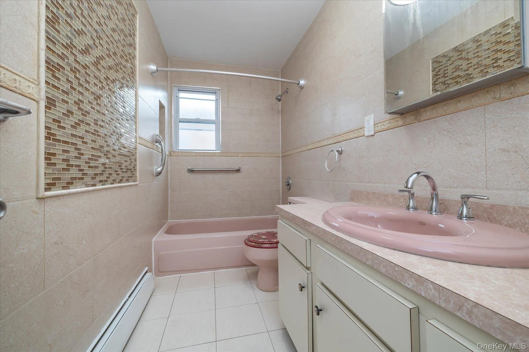 Bathroom featuring tile walls, a baseboard heating unit, vanity, shower / tub combination, and light tile patterned floors Bathroom featuring tile walls, a baseboard heating unit, vanity, shower / tub combination, and light tile patterned floors