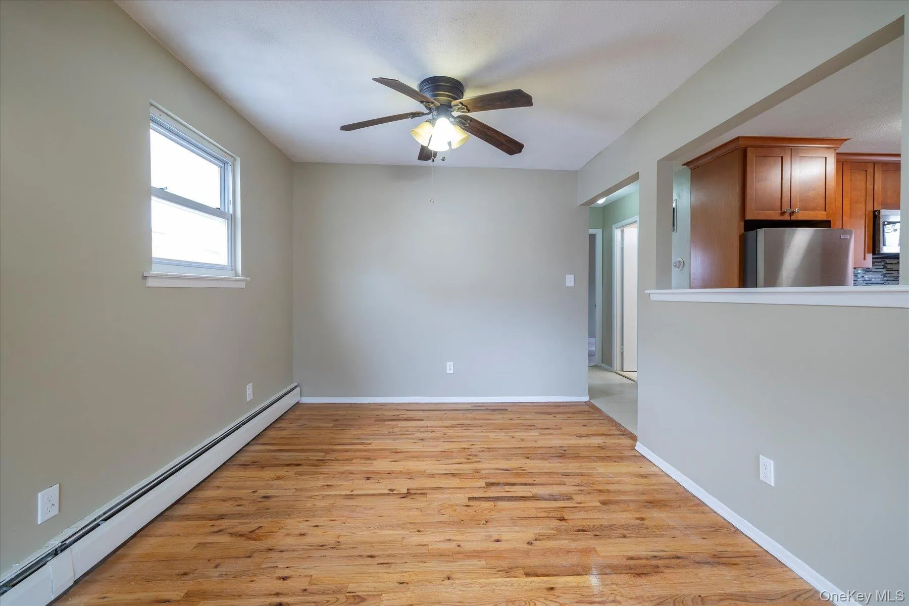 Spare room with a baseboard radiator, light wood-type flooring, and ceiling fan Spare room with a baseboard radiator, light wood-type flooring, and ceiling fan