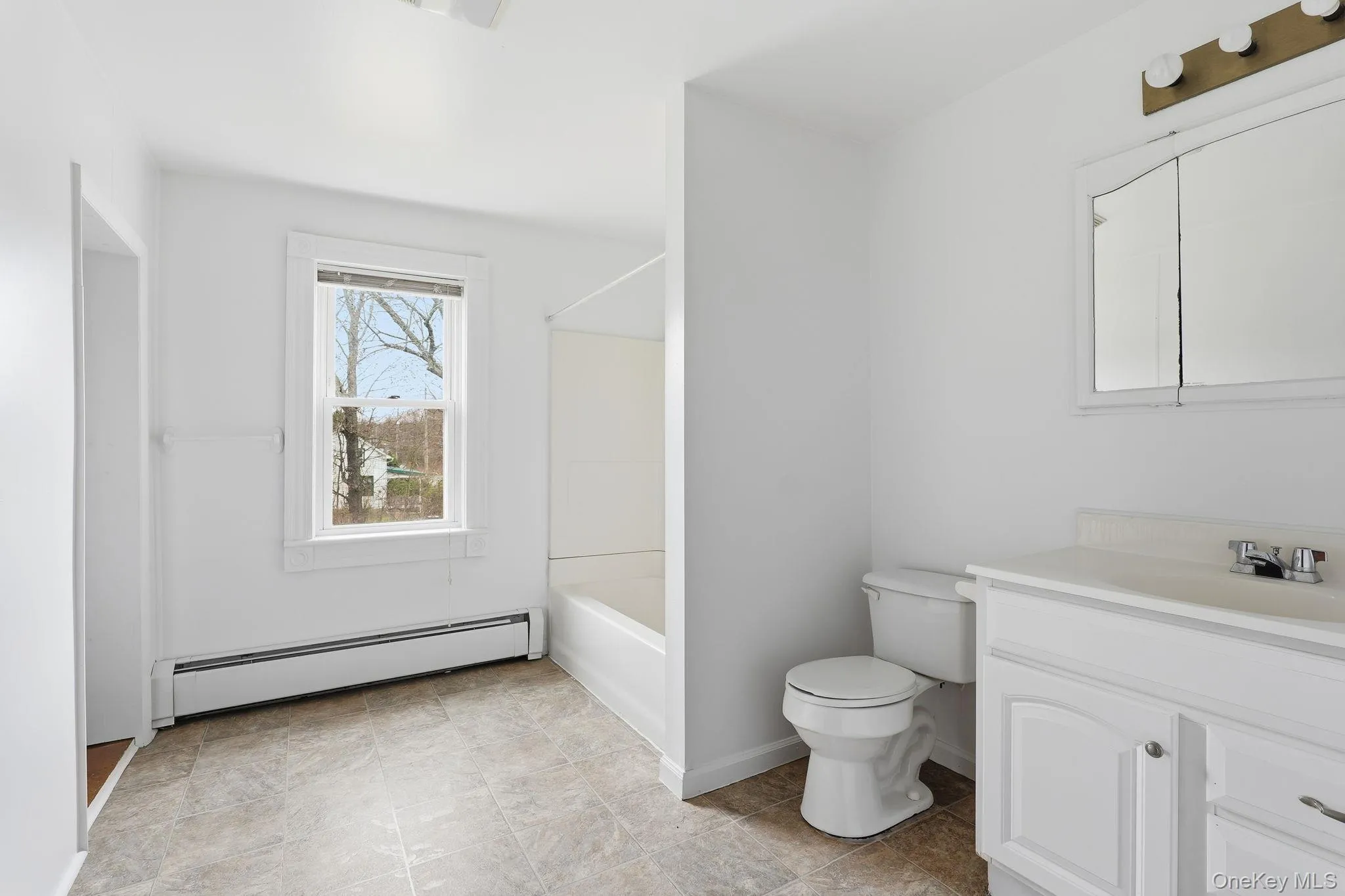 Bathroom featuring a baseboard heating unit, vanity, and bathtub / shower combination Bathroom featuring a baseboard heating unit, vanity, and bathtub / shower combination