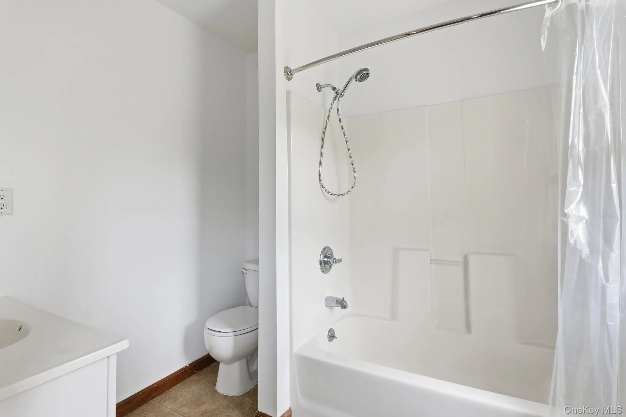 Bathroom with vanity, shower / bath combo with shower curtain, and light tile patterned flooring Bathroom with vanity, shower / bath combo with shower curtain, and light tile patterned flooring