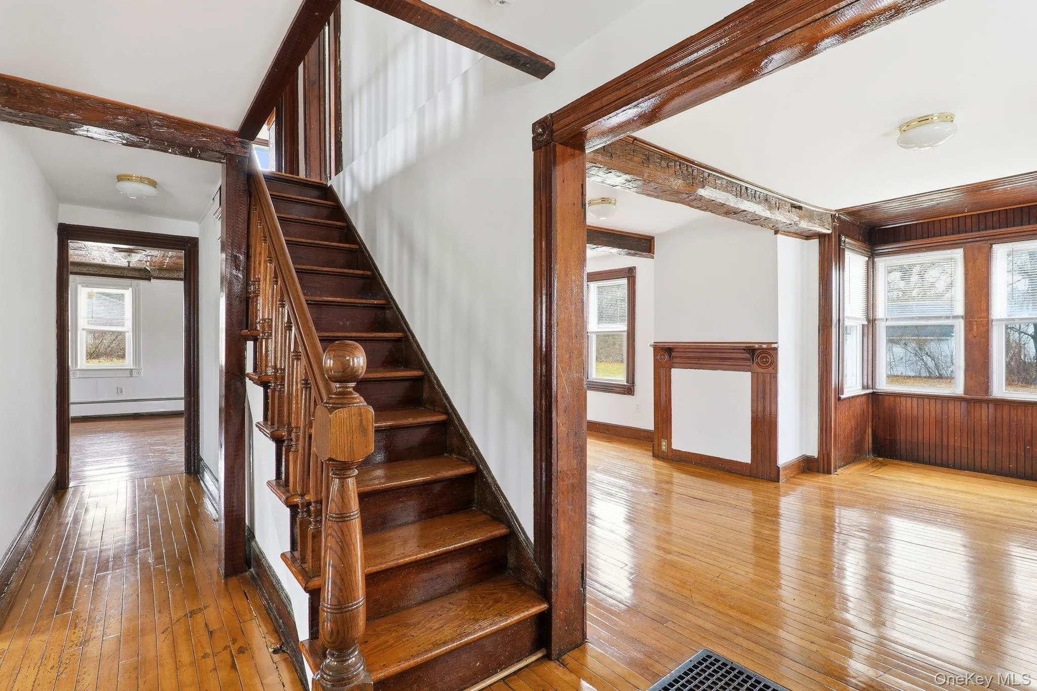 Stairs with healthy amount of natural light, hardwood / wood-style flooring, baseboard heating, and beamed ceiling Stairs with healthy amount of natural light, hardwood / wood-style flooring, baseboard heating, and beamed ceiling