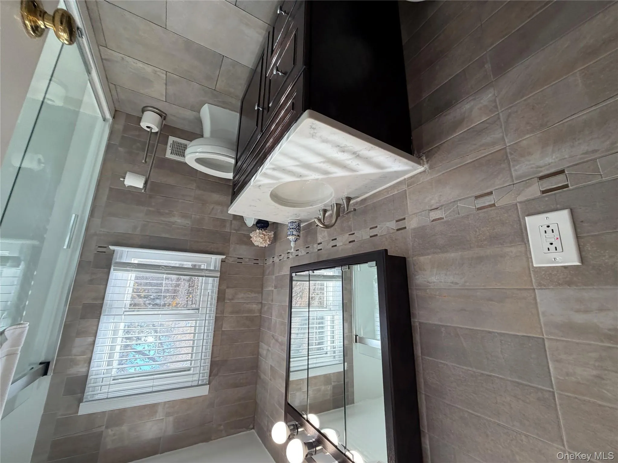 Bathroom featuring vanity, tile walls, light tile patterned floors, and a shower with shower door Bathroom featuring vanity, tile walls, light tile patterned floors, and a shower with shower door