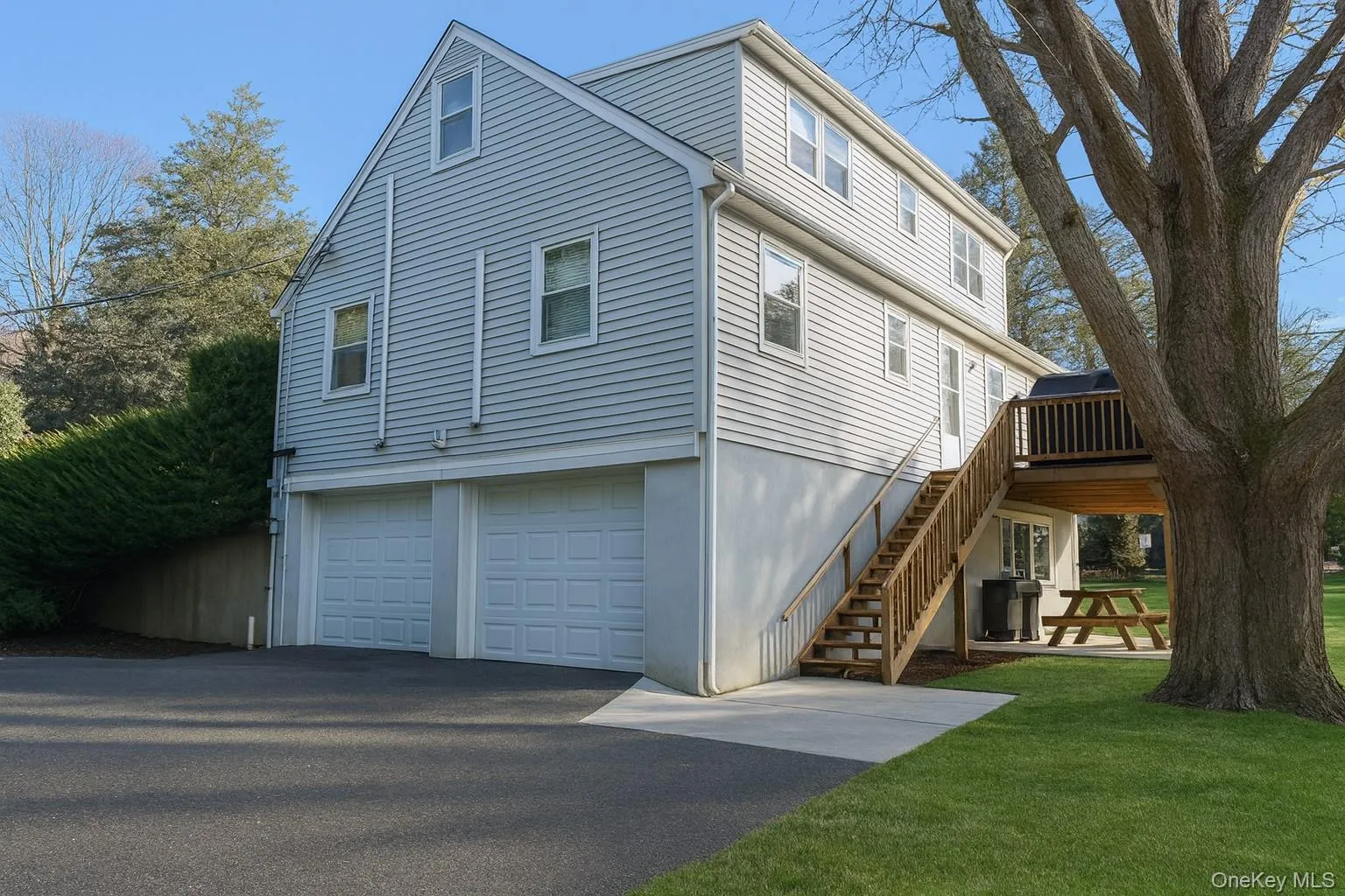 View of home's exterior with a wooden deck, stairway, a lawn, and asphalt driveway View of home's exterior with a wooden deck, stairway, a lawn, and asphalt driveway