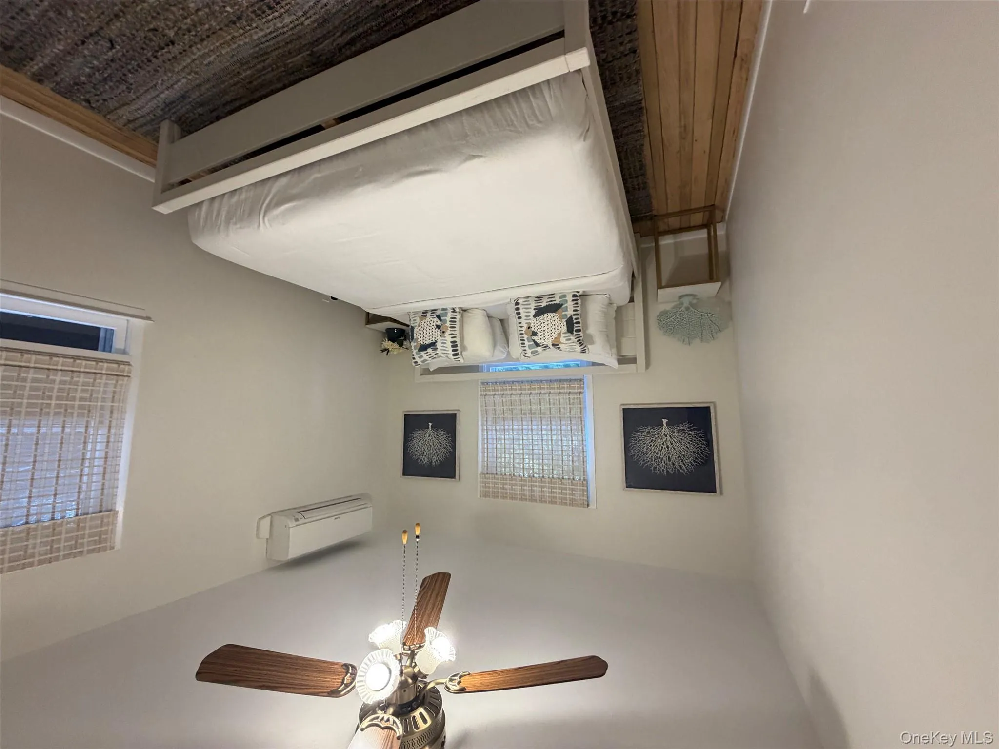 Bedroom with a ceiling fan, wood finished floors, and an AC wall unit Bedroom with a ceiling fan, wood finished floors, and an AC wall unit