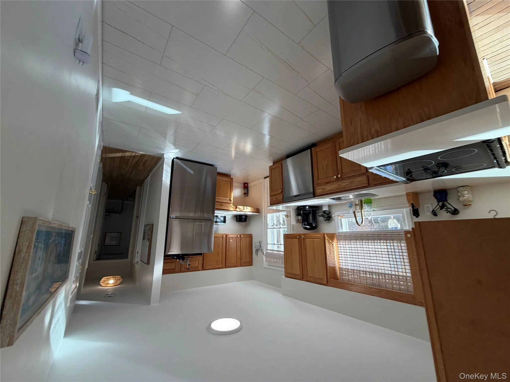 Kitchen featuring light countertops, stainless steel appliances, and brown cabinets Kitchen featuring light countertops, stainless steel appliances, and brown cabinets