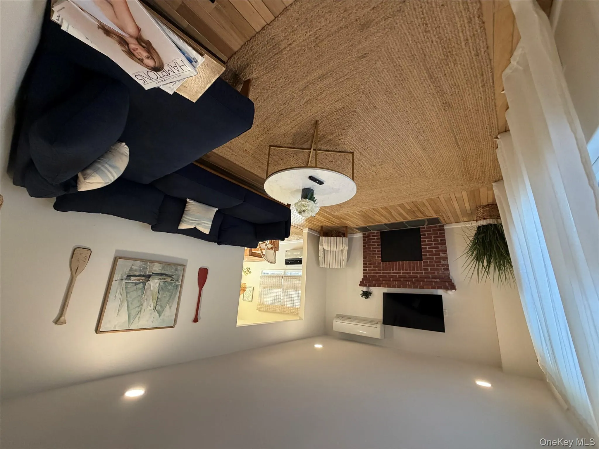 Living area featuring wood finished floors, a brick fireplace, recessed lighting, and an AC wall unit Living area featuring wood finished floors, a brick fireplace, recessed lighting, and an AC wall unit