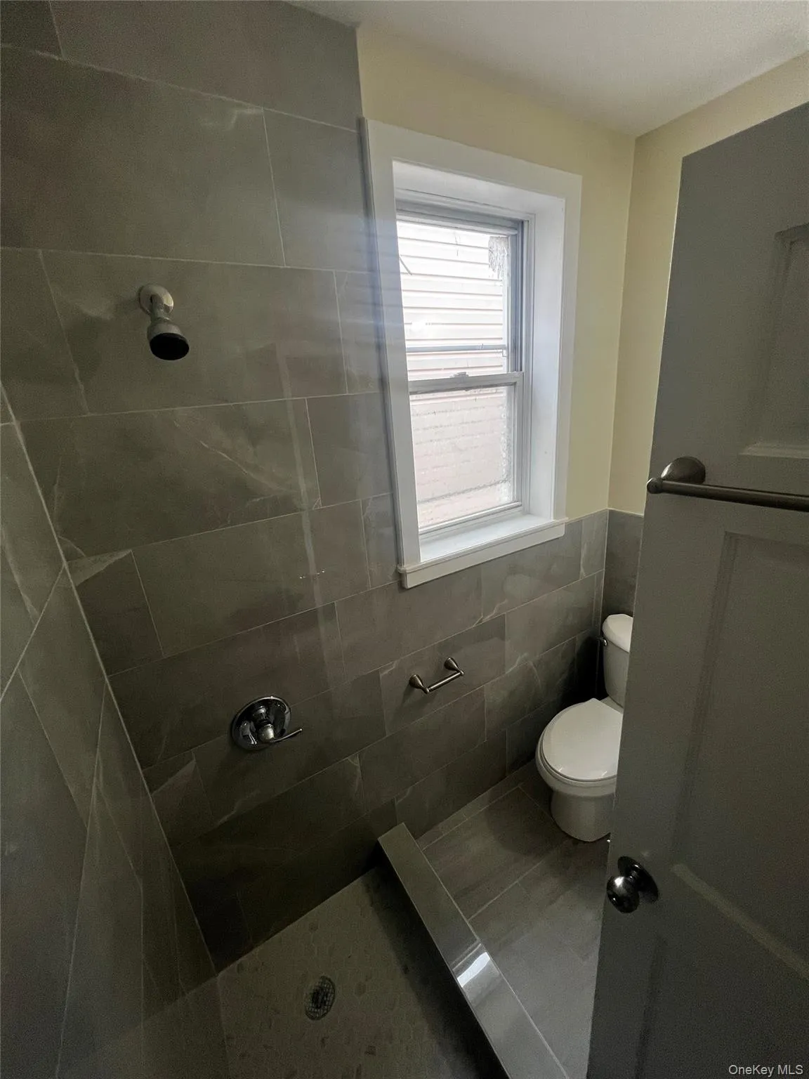 Full bathroom with a tile shower, tile walls, wainscoting, and tile patterned floors Full bathroom with a tile shower, tile walls, wainscoting, and tile patterned floors