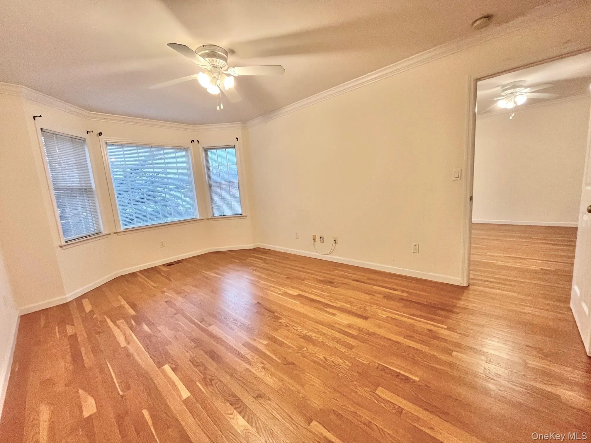 Empty room featuring a ceiling fan, light wood finished floors, and ornamental molding Empty room featuring a ceiling fan, light wood finished floors, and ornamental molding