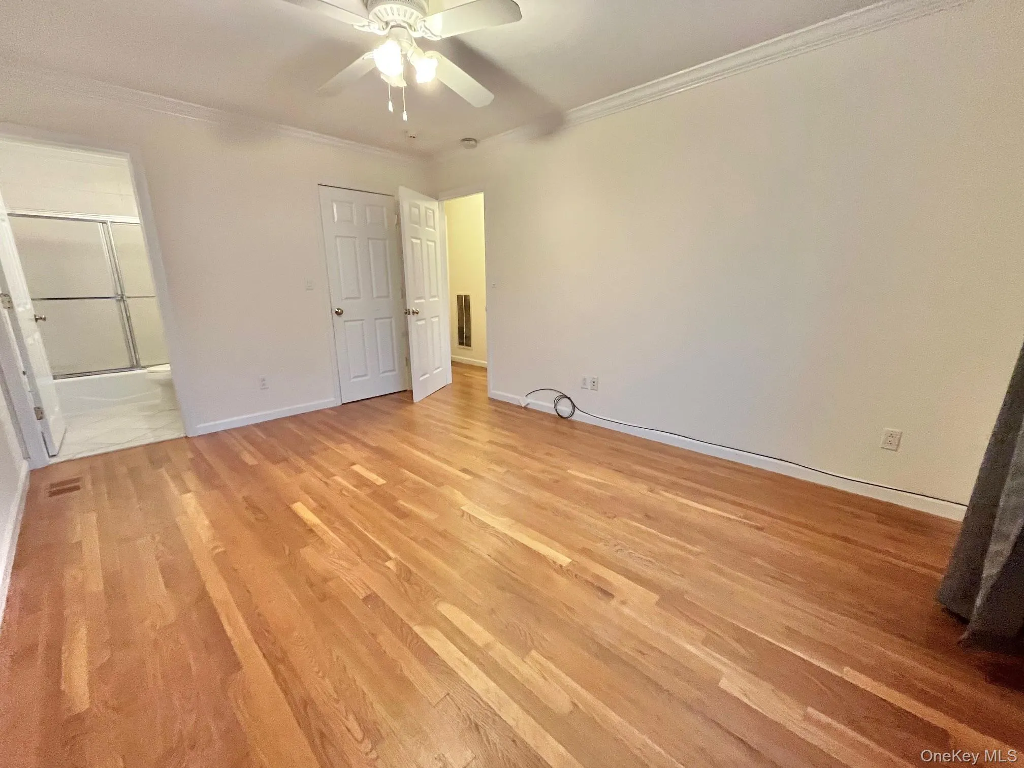 Unfurnished bedroom with crown molding, light wood finished floors, a ceiling fan, and ensuite bathroom Unfurnished bedroom with crown molding, light wood finished floors, a ceiling fan, and ensuite bathroom