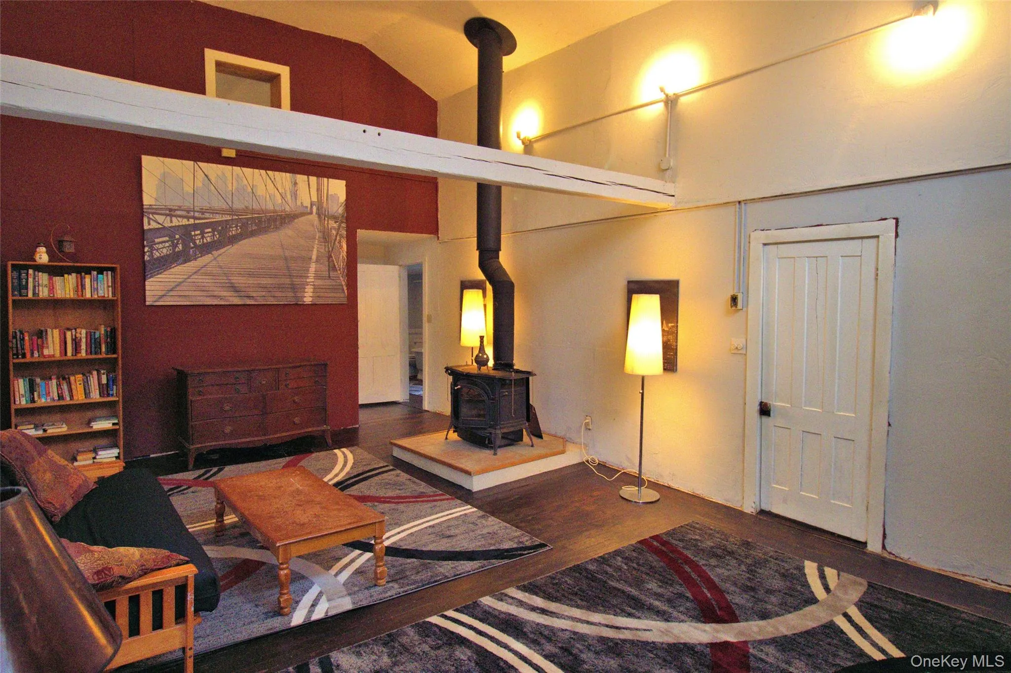 Living area with a wood stove, vaulted ceiling, and wood finished floors Living area with a wood stove, vaulted ceiling, and wood finished floors