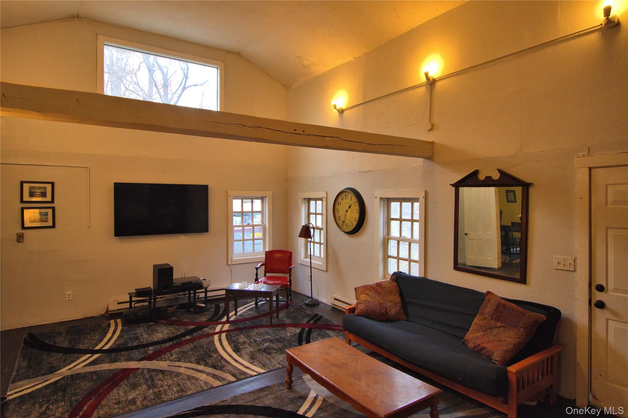 Living room with high vaulted ceiling, baseboard heating, and a baseboard heating unit Living room with high vaulted ceiling, baseboard heating, and a baseboard heating unit