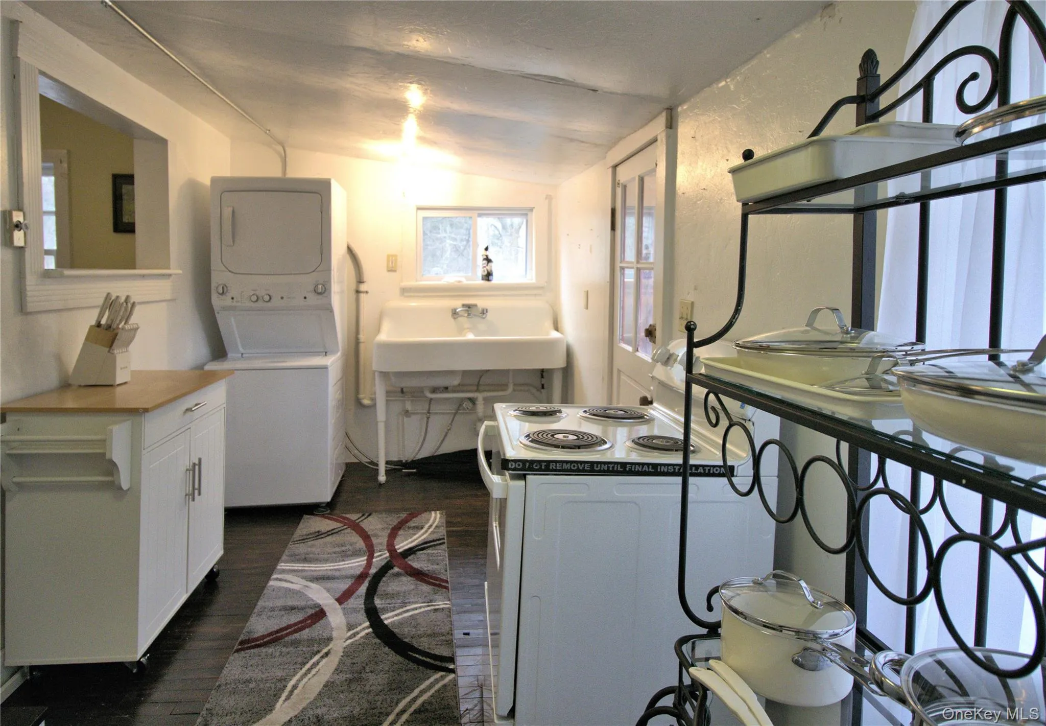 Washroom with lofted ceiling, dark wood-style floors, and stacked washer / drying machine Washroom with lofted ceiling, dark wood-style floors, and stacked washer / drying machine