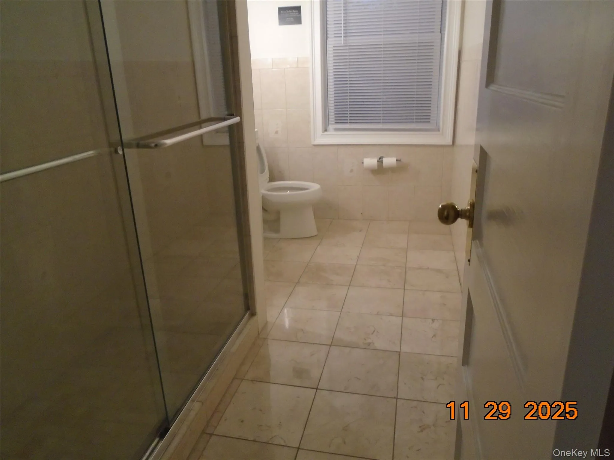 Bathroom featuring a shower stall, tile walls, and light tile patterned floors Bathroom featuring a shower stall, tile walls, and light tile patterned floors