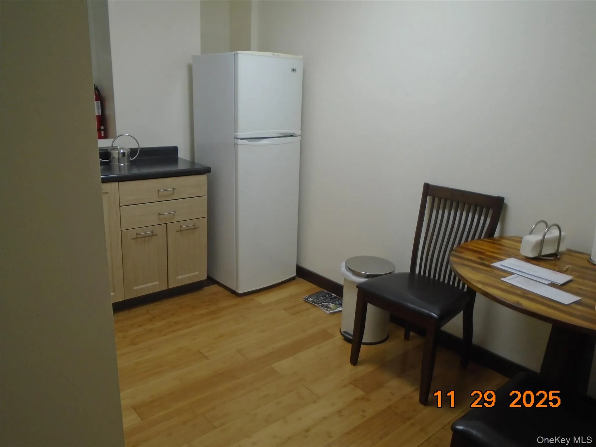 Kitchen featuring light brown cabinetry, freestanding refrigerator, dark countertops, and light wood-type flooring Kitchen featuring light brown cabinetry, freestanding refrigerator, dark countertops, and light wood-type flooring