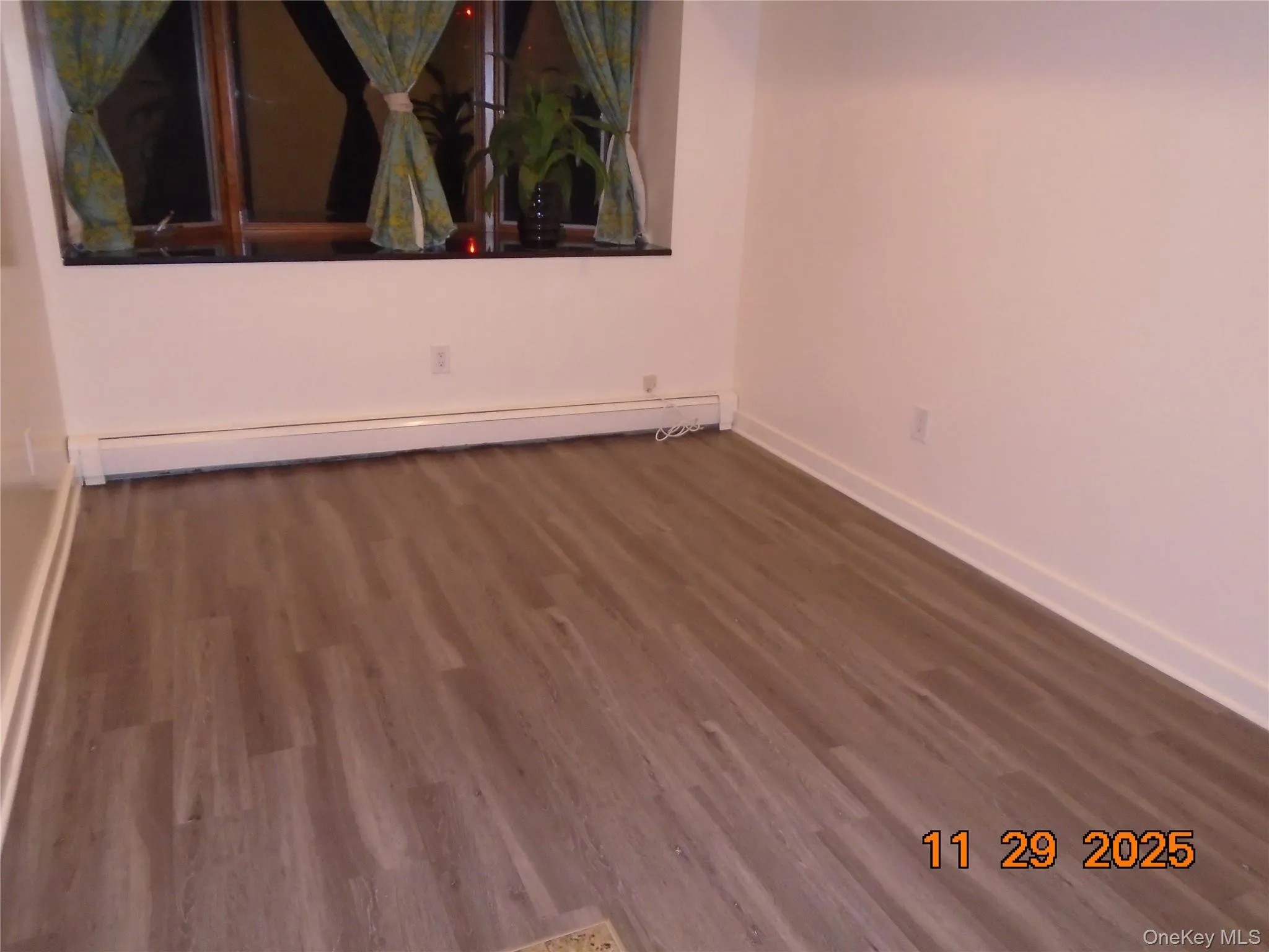 Spare room featuring a baseboard heating unit and dark wood-style floors Spare room featuring a baseboard heating unit and dark wood-style floors