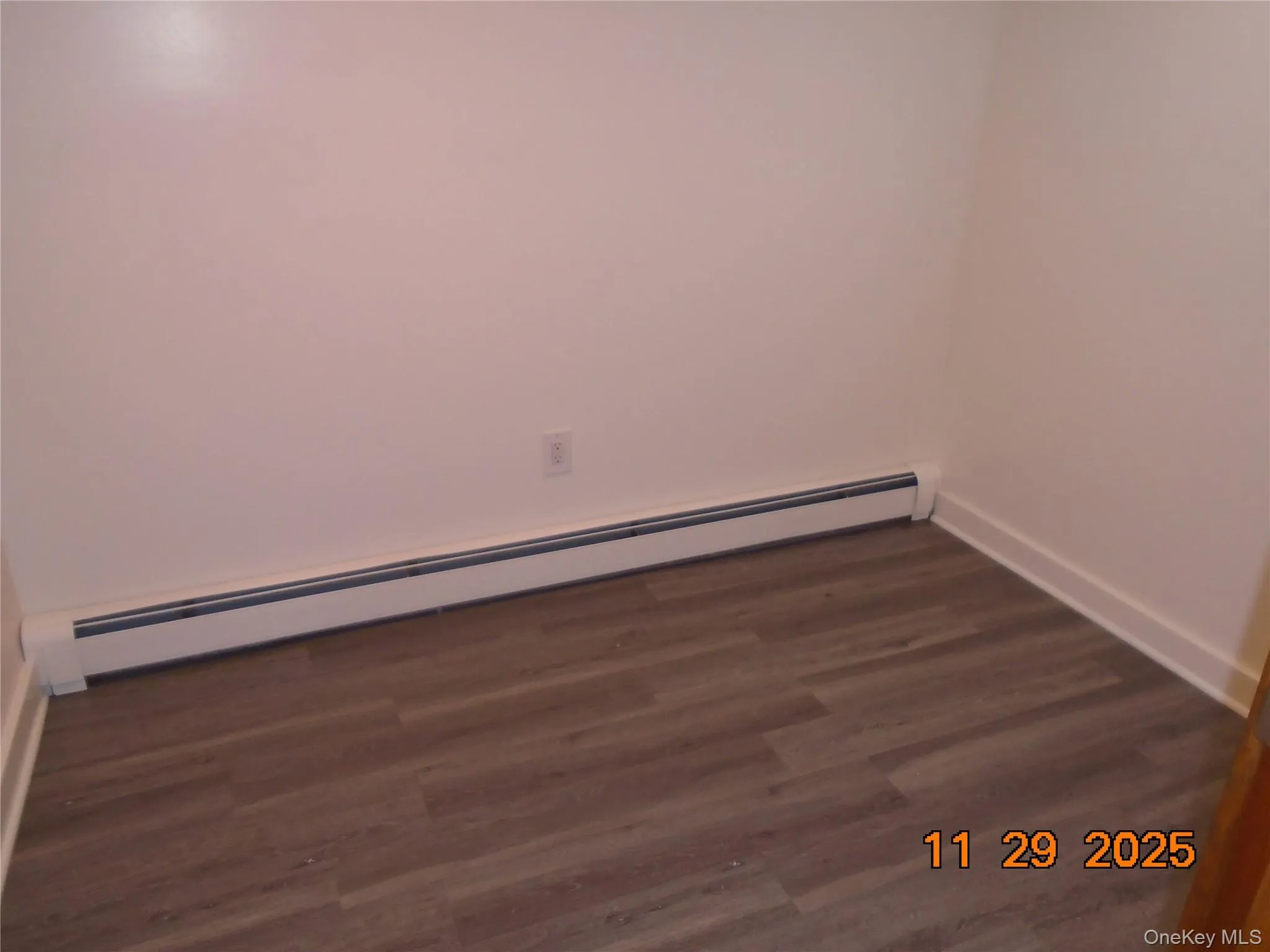 Unfurnished room featuring a baseboard heating unit and dark wood-style floors Unfurnished room featuring a baseboard heating unit and dark wood-style floors