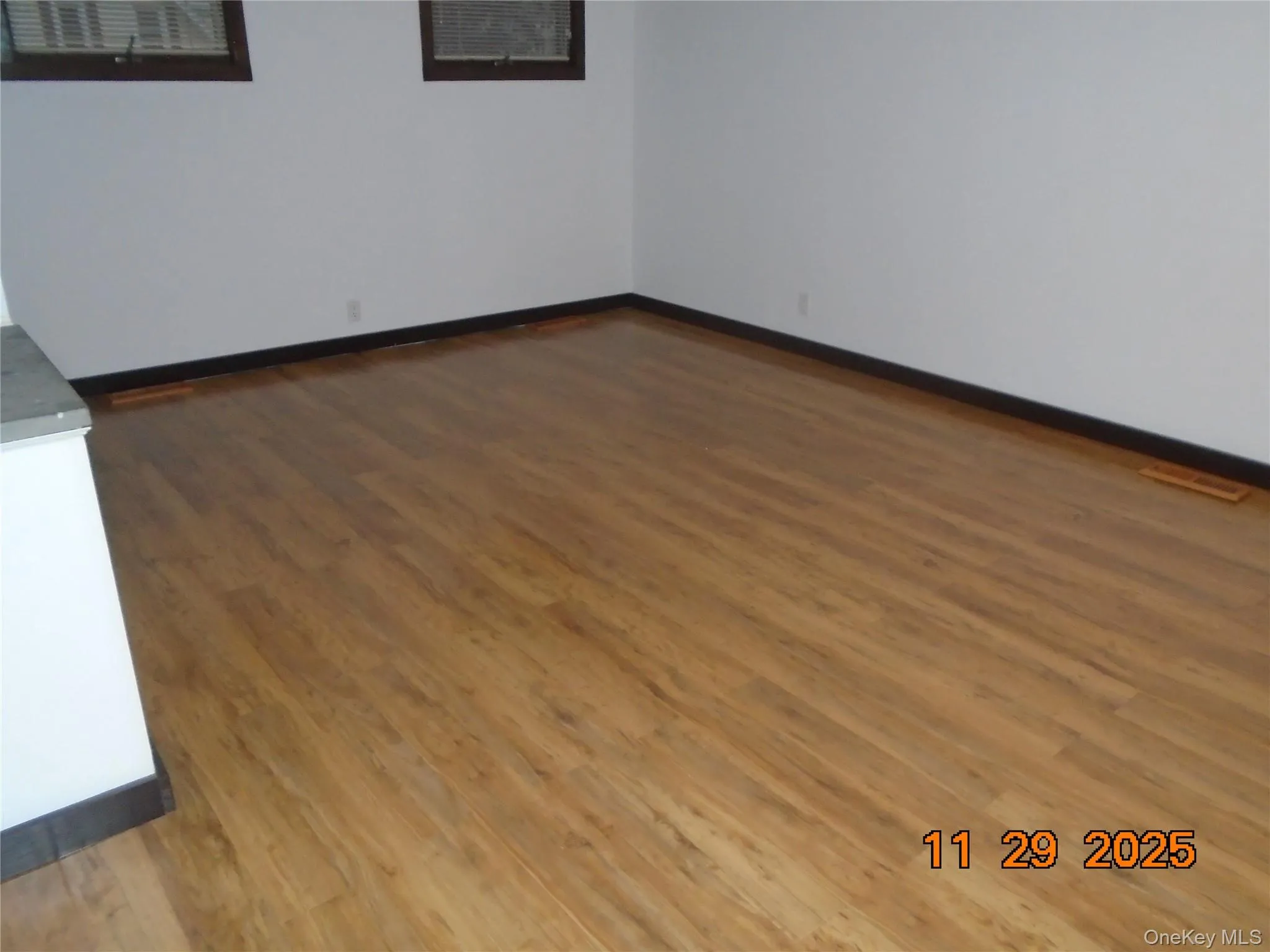 Spare room with baseboards and dark wood-style flooring Spare room with baseboards and dark wood-style flooring