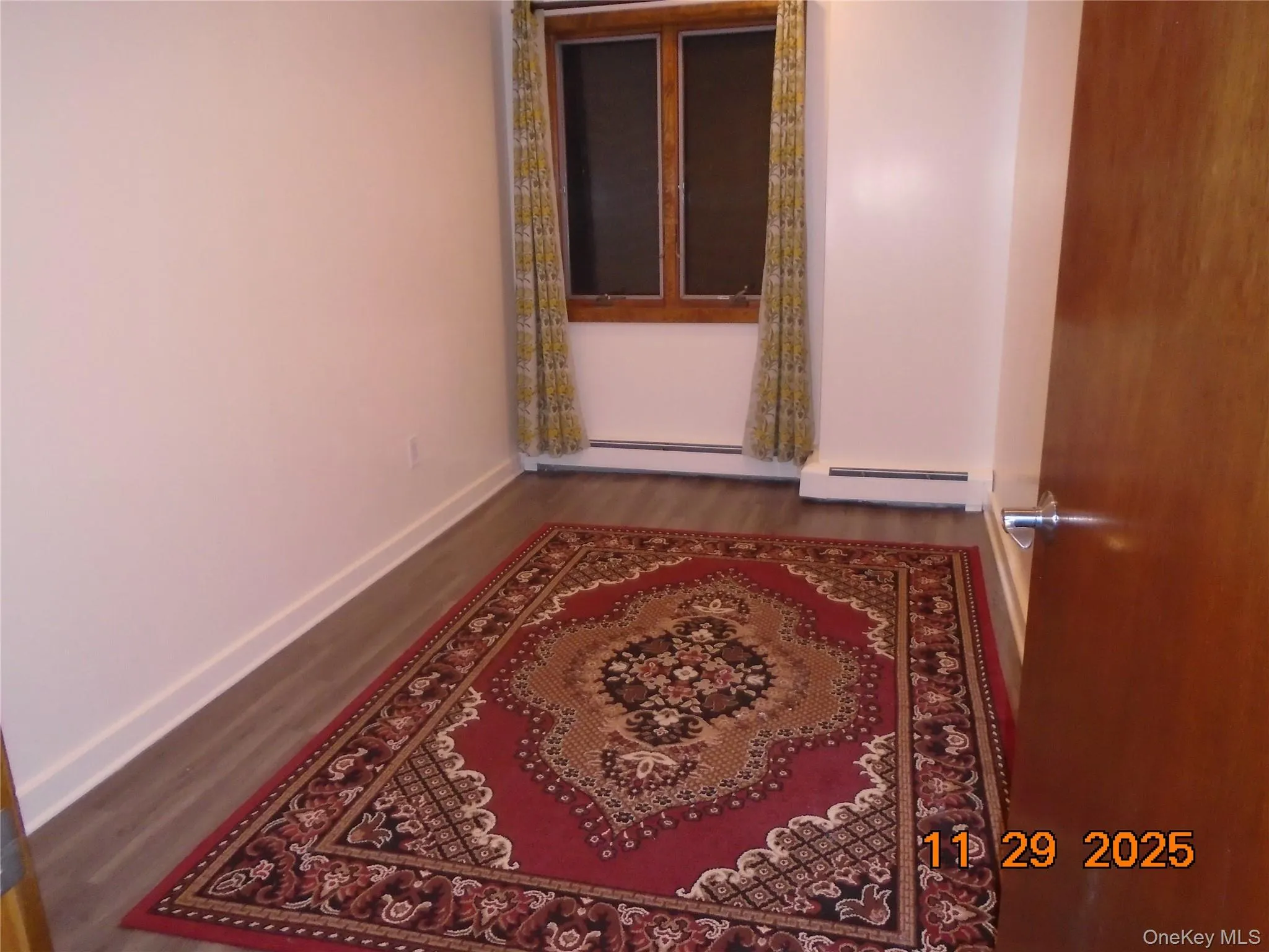 Unfurnished room featuring wood finished floors and a baseboard radiator Unfurnished room featuring wood finished floors and a baseboard radiator